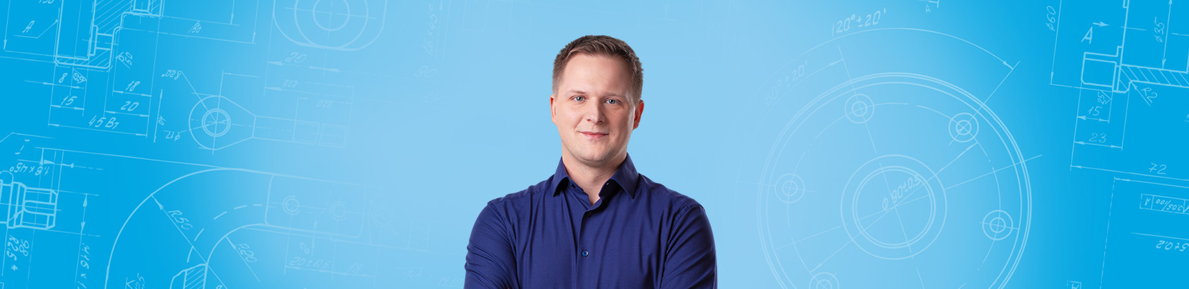 Picture shows a blonde man in front of a light blue background wearing a blue shirt and smiling into the camera.