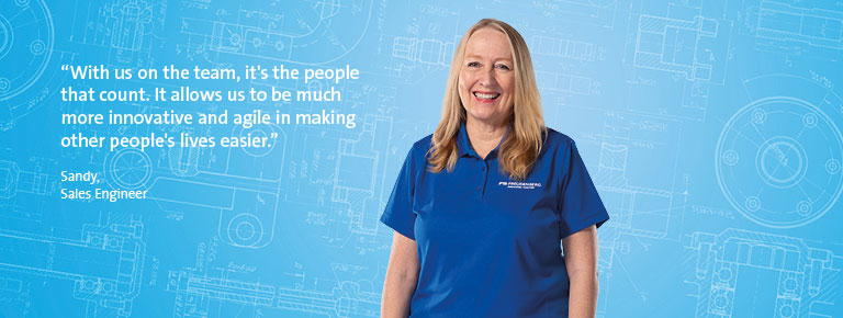 A blonde woman smiling at the camera, wearing a blue shirt and standing in front of a blue background. There is a quote in the left part of the picture.