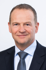 Profil picture showing Dr. Frank Heislitz, CTO of the Freudenberg Group, wearing a dark blue suit and a tie.