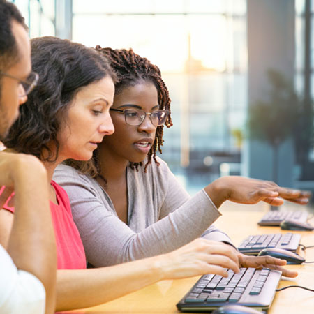 Three people sitting next to each other in front of a computer
