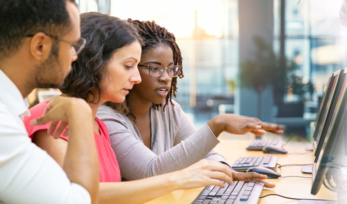 Three people sitting next to each other in front of a computer
