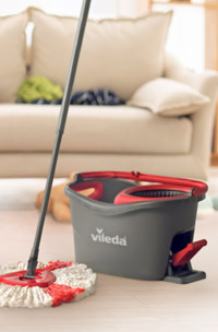 a vileda mop an bucket in a living room with a couch in the background