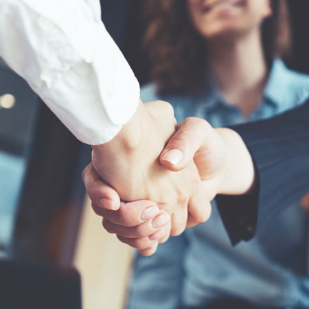Close up of a hand shake of two people with a blurred women in the background