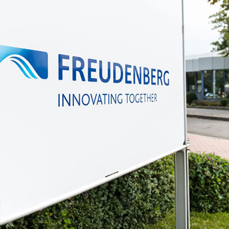 White sign that has written Freudenberg Innovation Together in blue letters