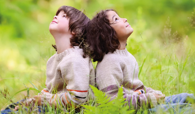The picture shows children leaning on each other's backs, sitting on the grass and looking up at the sky