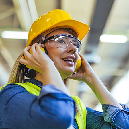 Fabrikarbeiterin in Schutzkleidung in industrieller Produktionsumgebung
