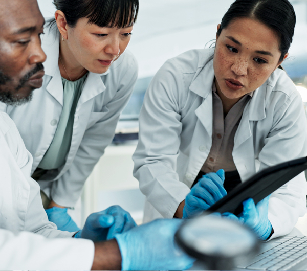 Three employees looking at a tablet in a laboratory
