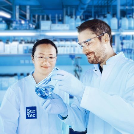 SurTec employees in lab coats inspecting a blue liquid in a beaker