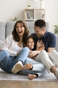 a woman, a man and a girl sitting on the floor and laughing