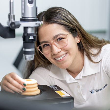 A woman works on a device in the laboratory and looks friendly into the camera