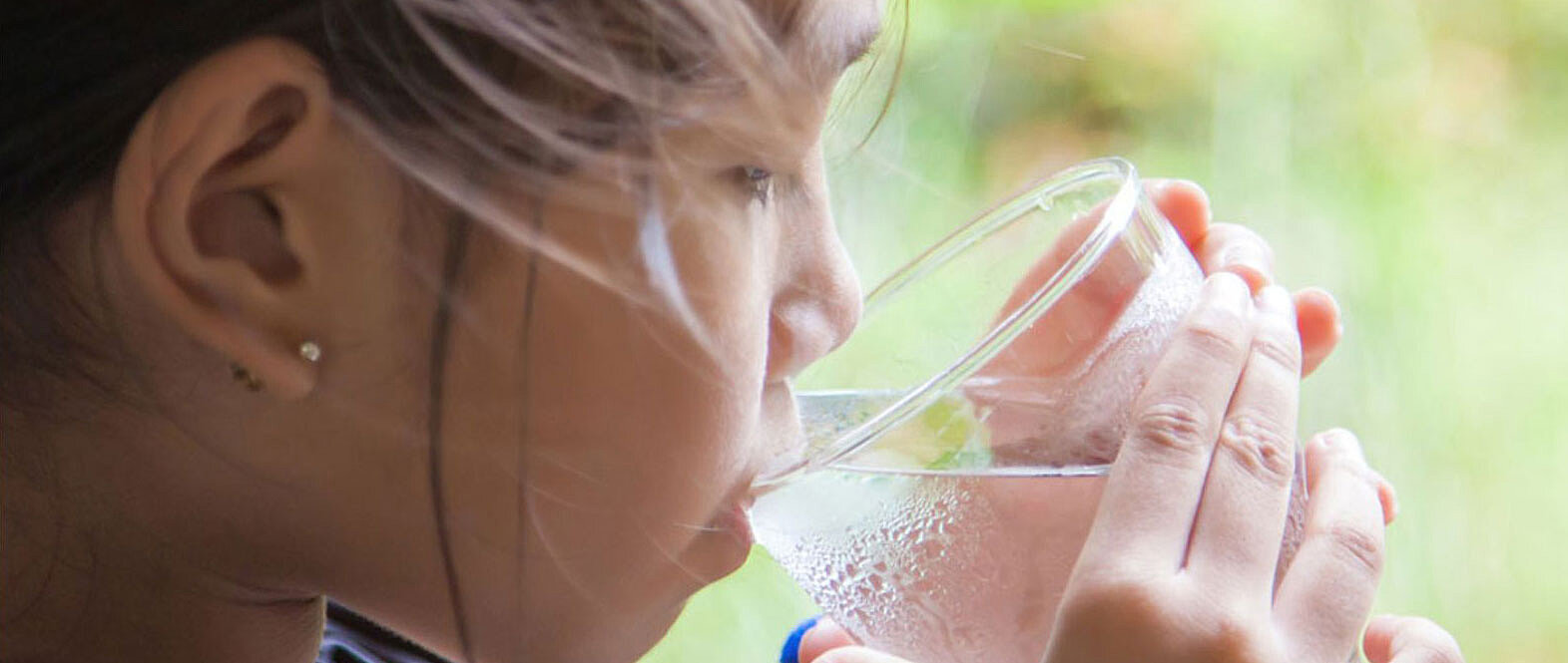 a little girl drinking water from a glass