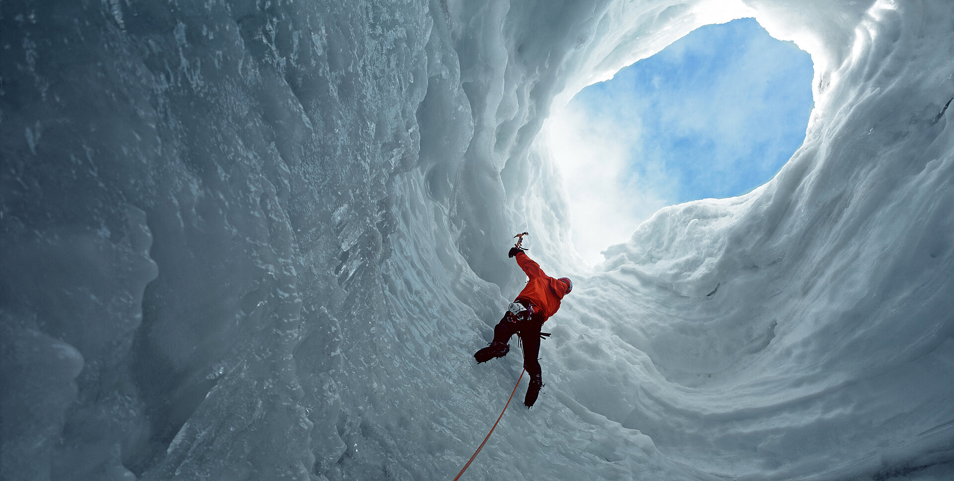 man climbing towards an opening in an icecave at Langjokull glacier