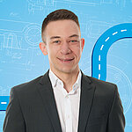 Portrait of a male person shown in the center of the picture against a blue background.
