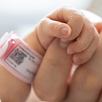 a tiny baby hand grabbing one finger of an adult hand