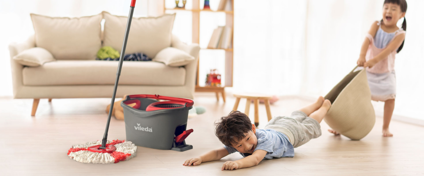 Close up of a grey cleaning bucket and children playing next to it