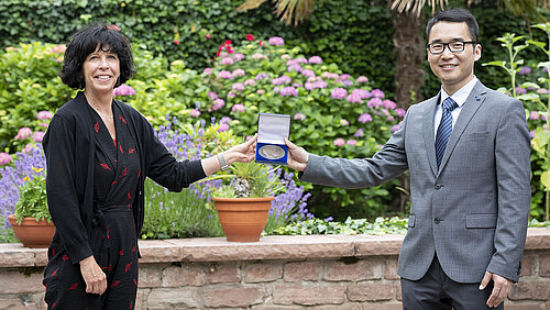 A woman hands a medal to a man in a small box.