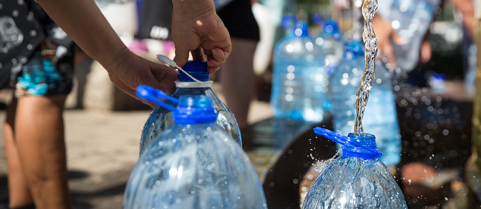 plastic bottles getting filled with water by chrildrens hands