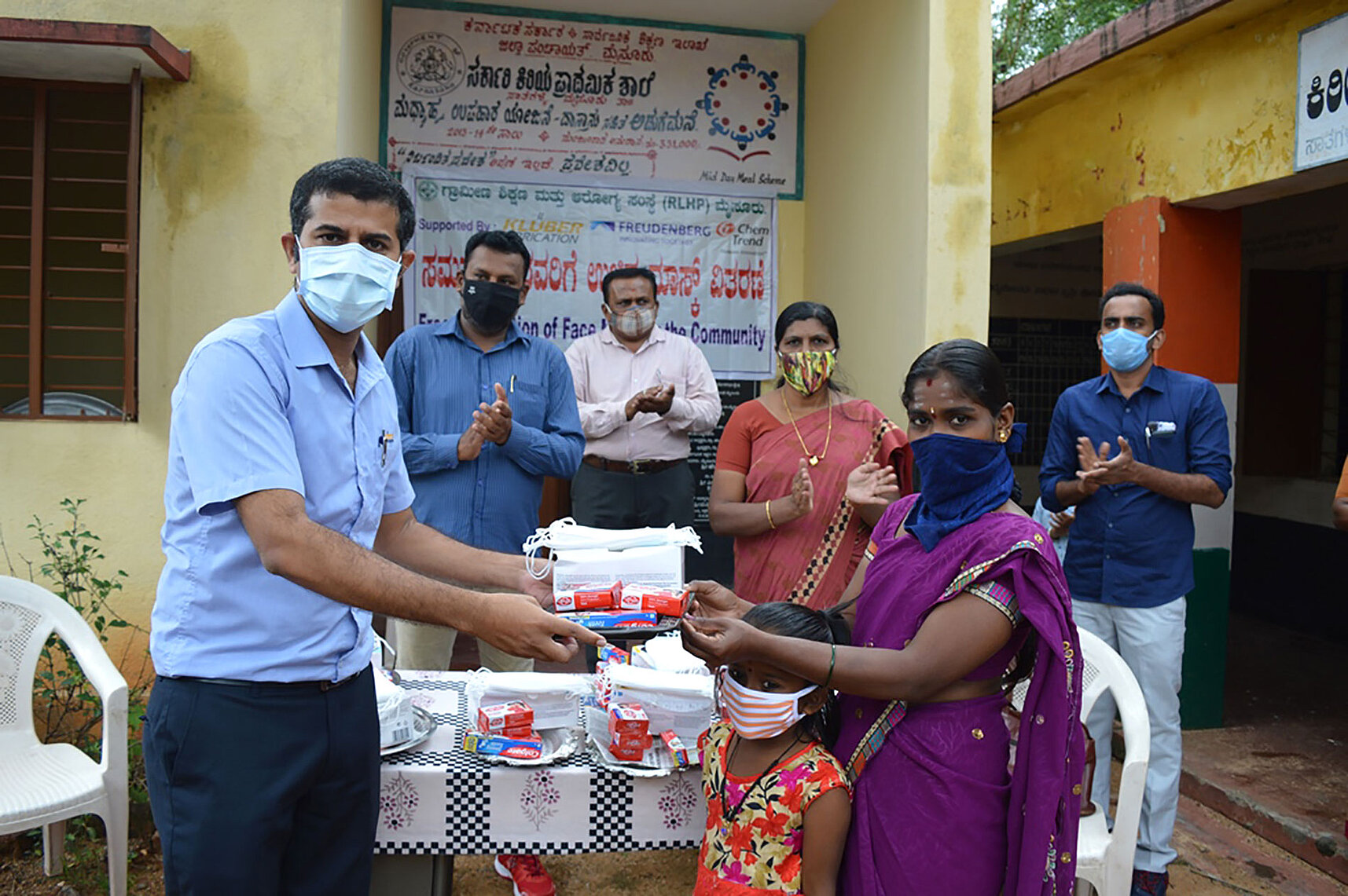 A man hands over soap, masks and toothpaste to a woman.