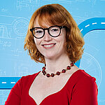 Portrait of a female person shown in the center of the picture against a blue background.