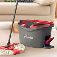 a vileda mop and a gray vileda bucket in front of a sofa