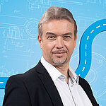Portrait of a male person shown in the center of the picture against a blue background.
