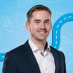 Portrait of a male person shown in the center of the picture against a blue background.