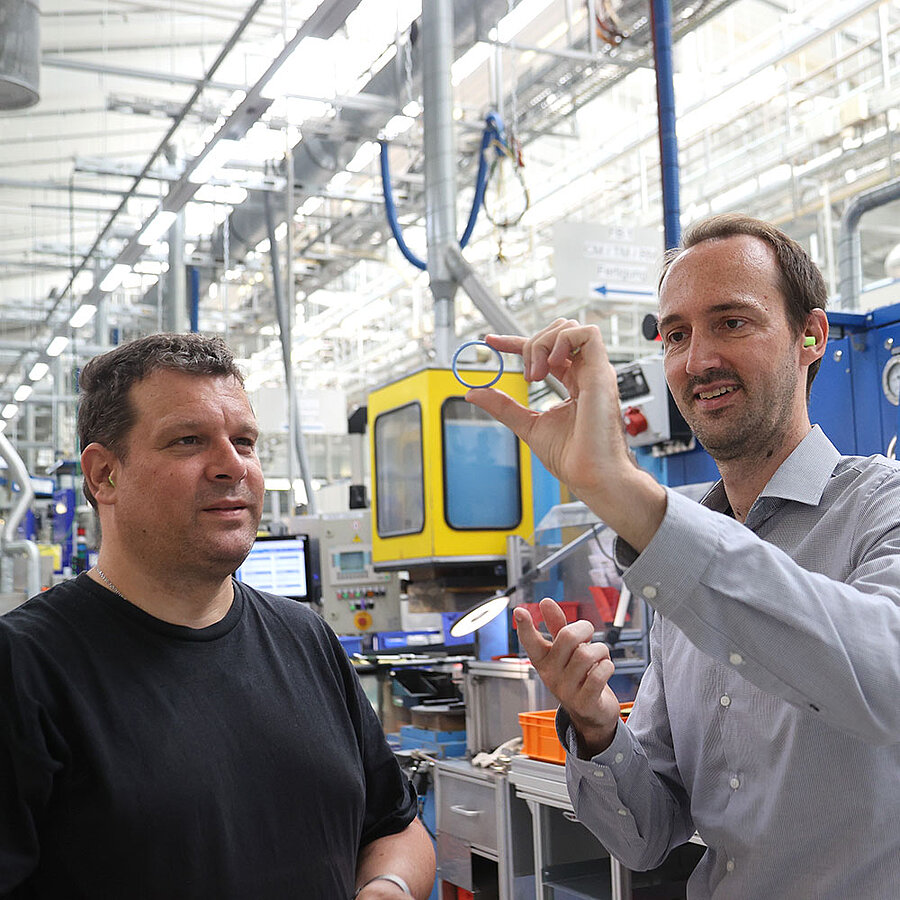 wo employees inspecting a sealing in an industrial manufacturing environment.