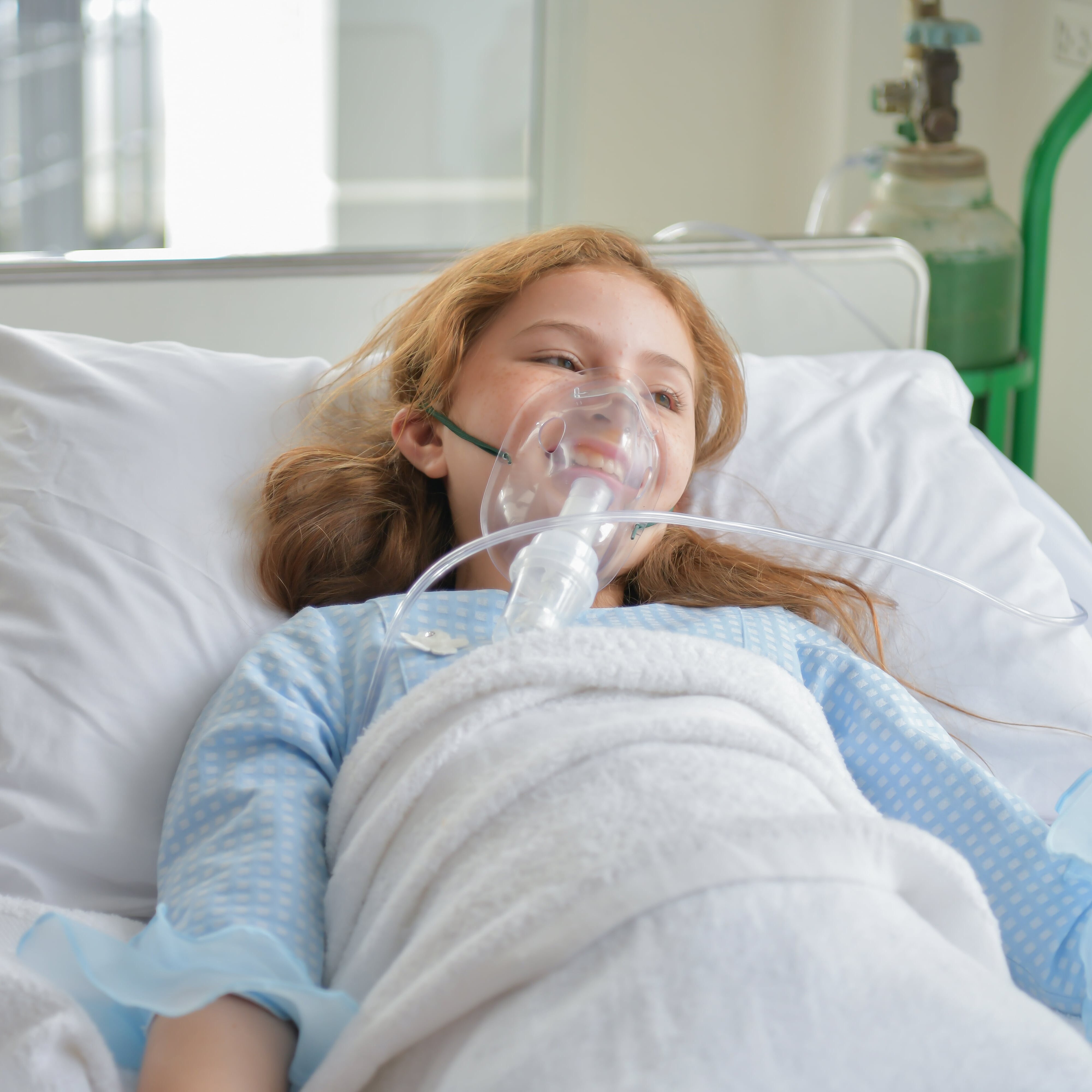 a girl in a hospital bed with an oxygen mask