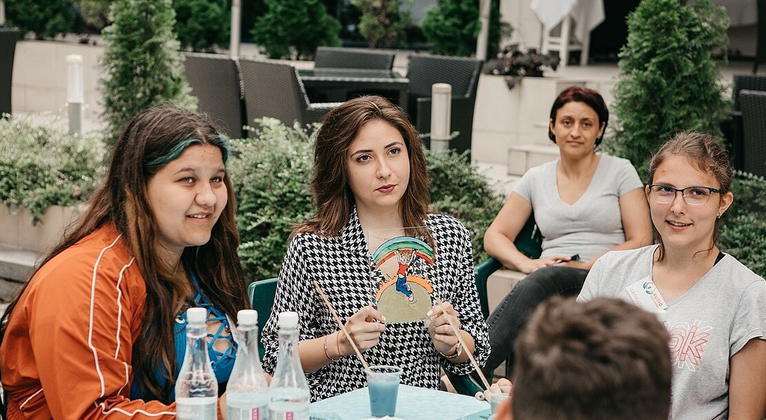 Young people sitting on a table and talking to each other