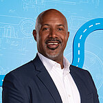 Portrait of a male person shown in the center of the picture against a blue background.