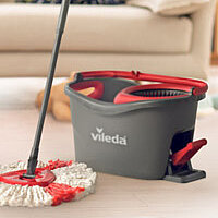 a vileda mop an bucket in a living room with a couch in the background