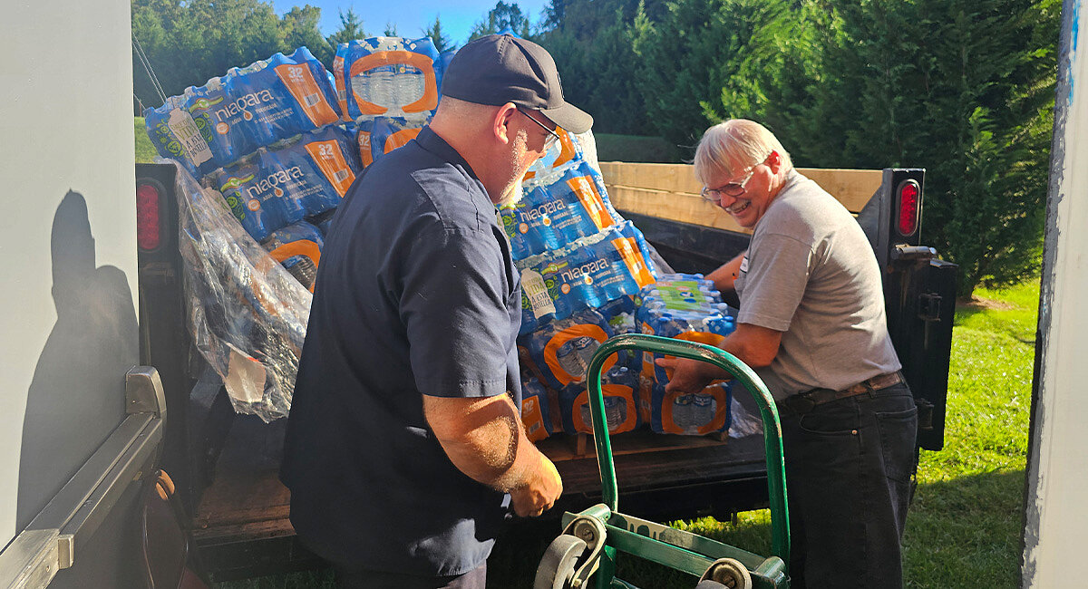  Picture shows two elderly men unloading water bottles from a truck