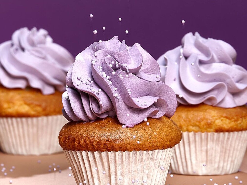 three muffins with violet frosting