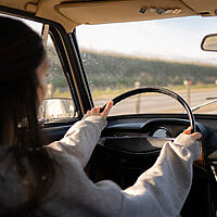 a woman from behind driving a car