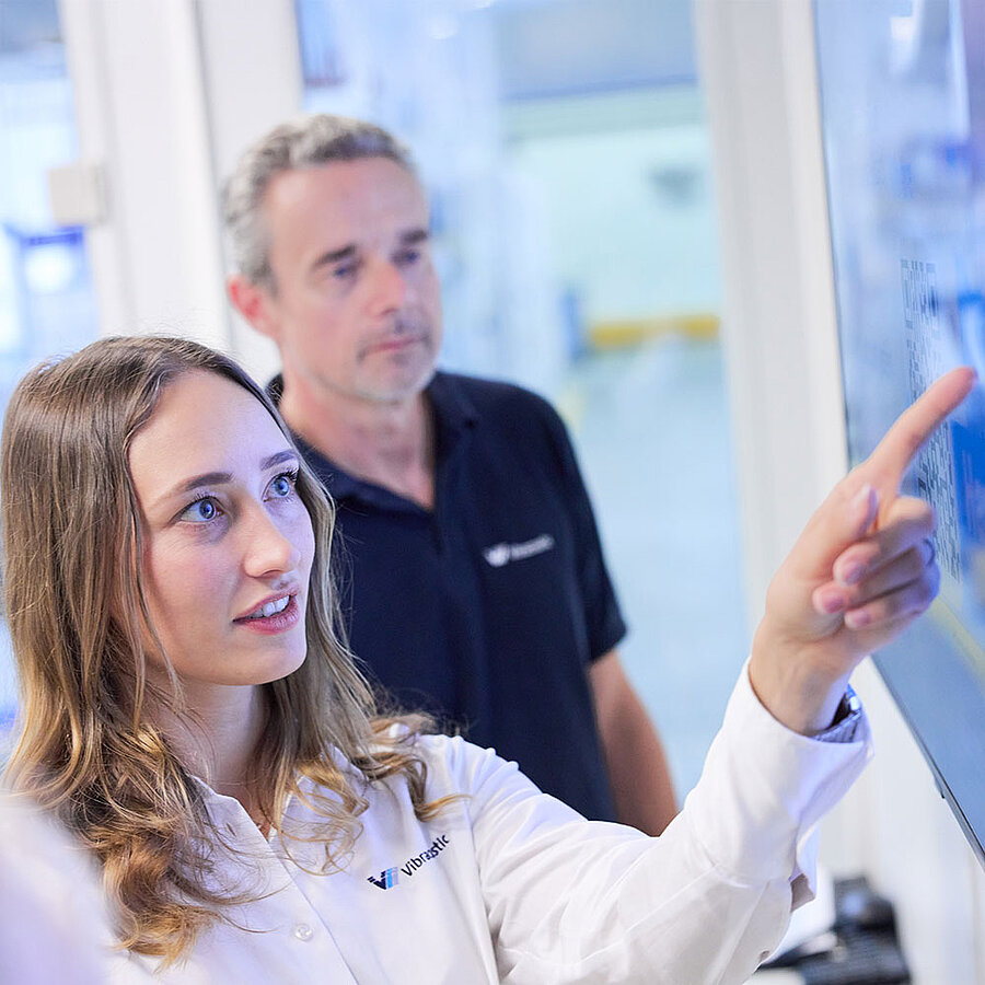 Two employees jointly reviewing information on a screen in a work environment.
