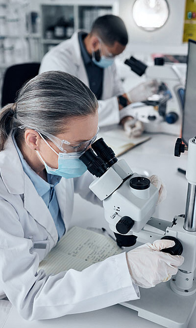 Two employees in lab coats working with microscopes