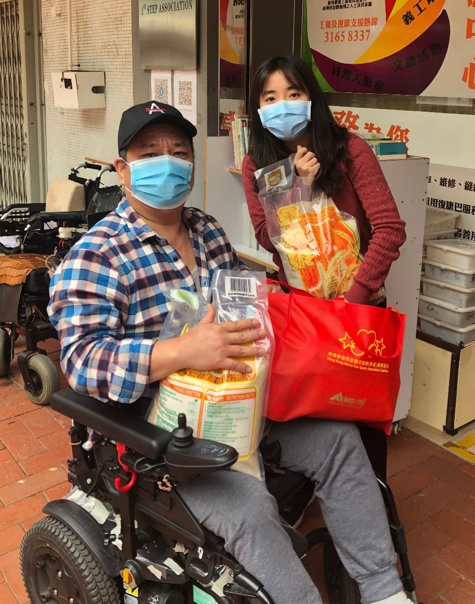 Man in wheelchair and woman standing next to him with food donation.