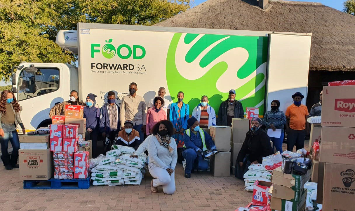 Eine Gruppe von Menschen mit Lebensmittelspenden vor einem LKW