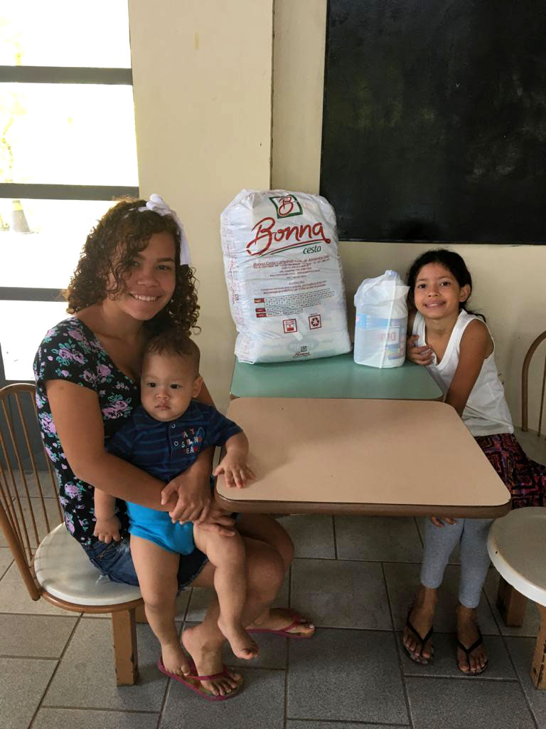 A young family sits at a table with food donations on it.