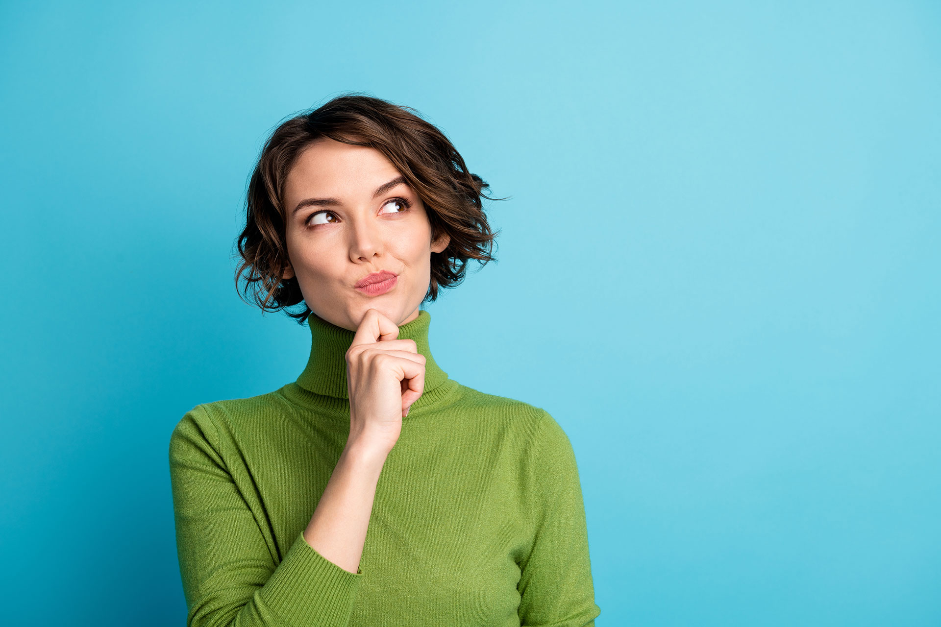 Portrait of minded interested woman with a green jumper an a finger on her chin